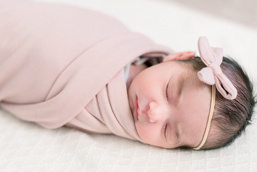 newborn girl in pink swaddle and bow