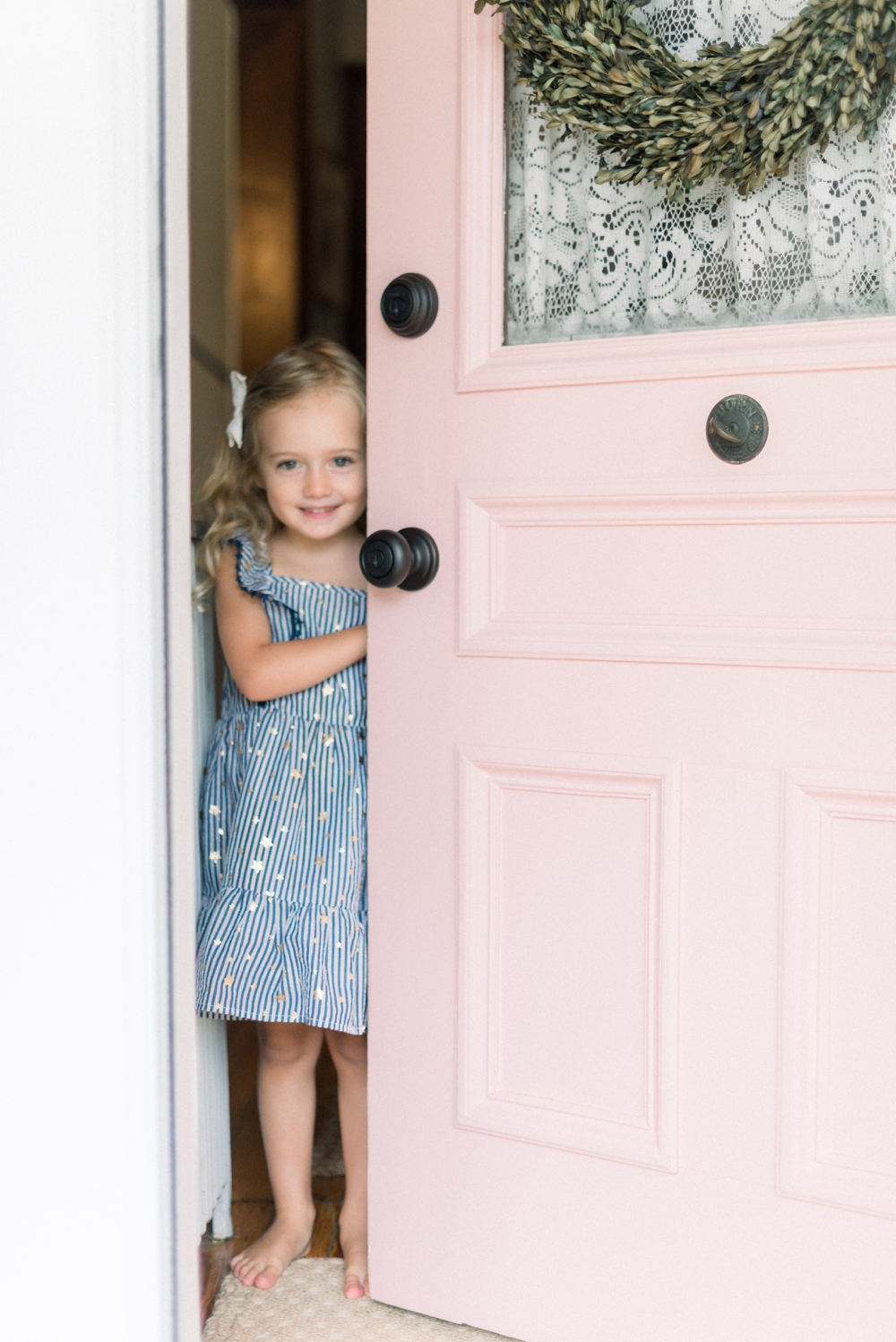 cute girl in blue dress with pink front door