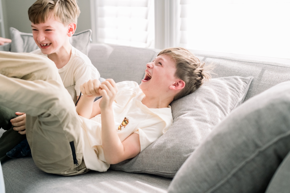 Young boys laughing on couch.