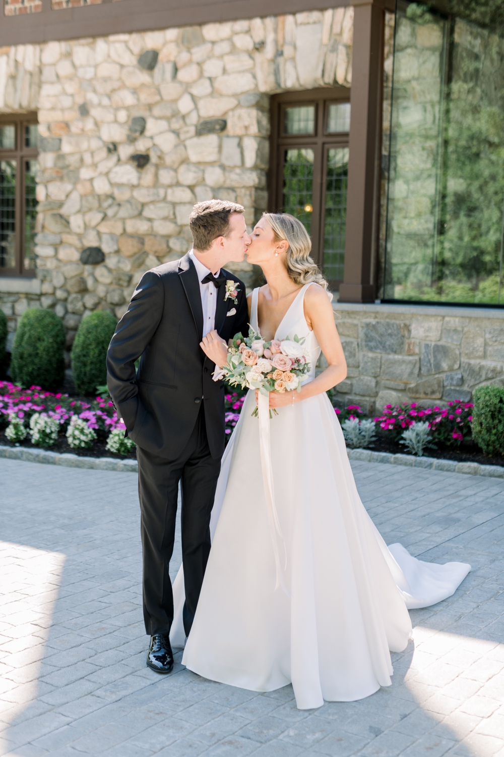 Newlyweds kiss in the patio lined with flowers at Le Chateau