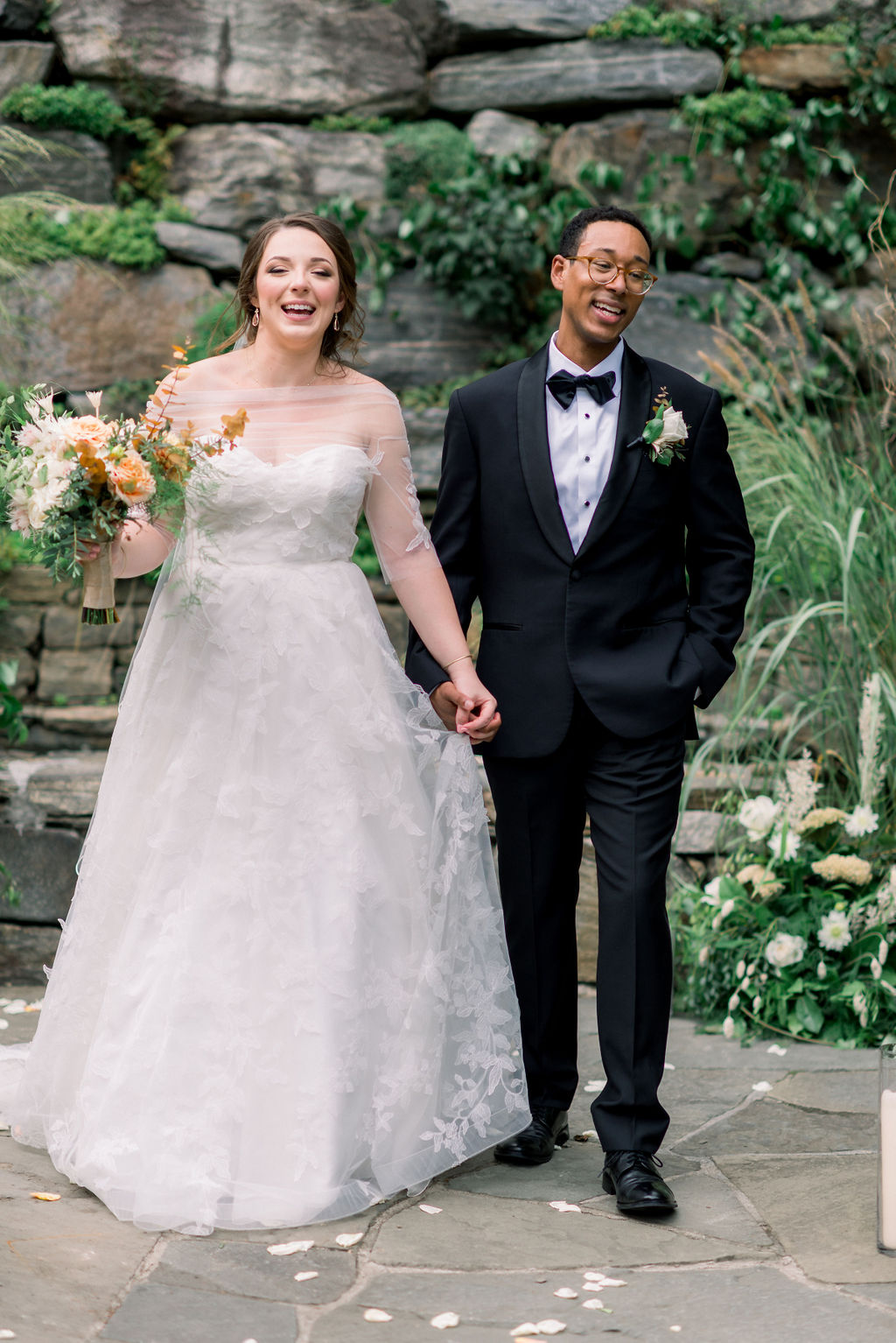 Newlyweds laugh and walk through the gardens holding hands at the Bedford Post Inn Wedding venue