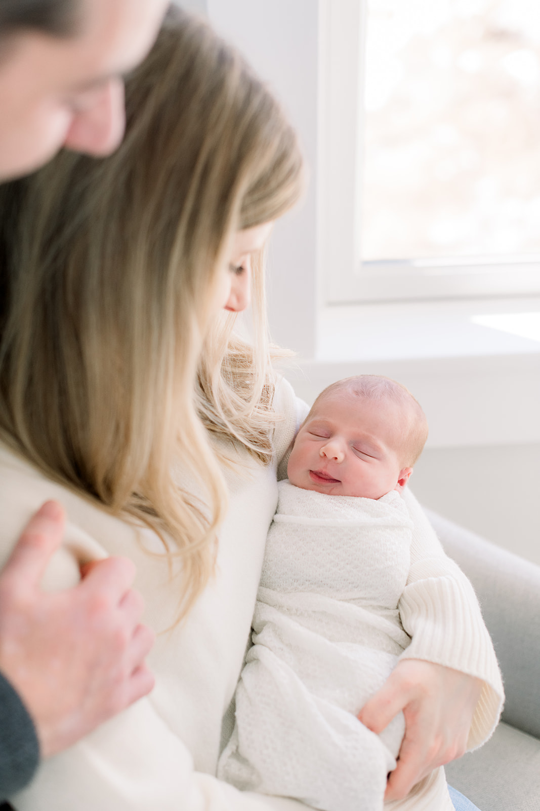 A smiling newborn baby sleeps in mom's arms in the nursery after using newborn photo session tips